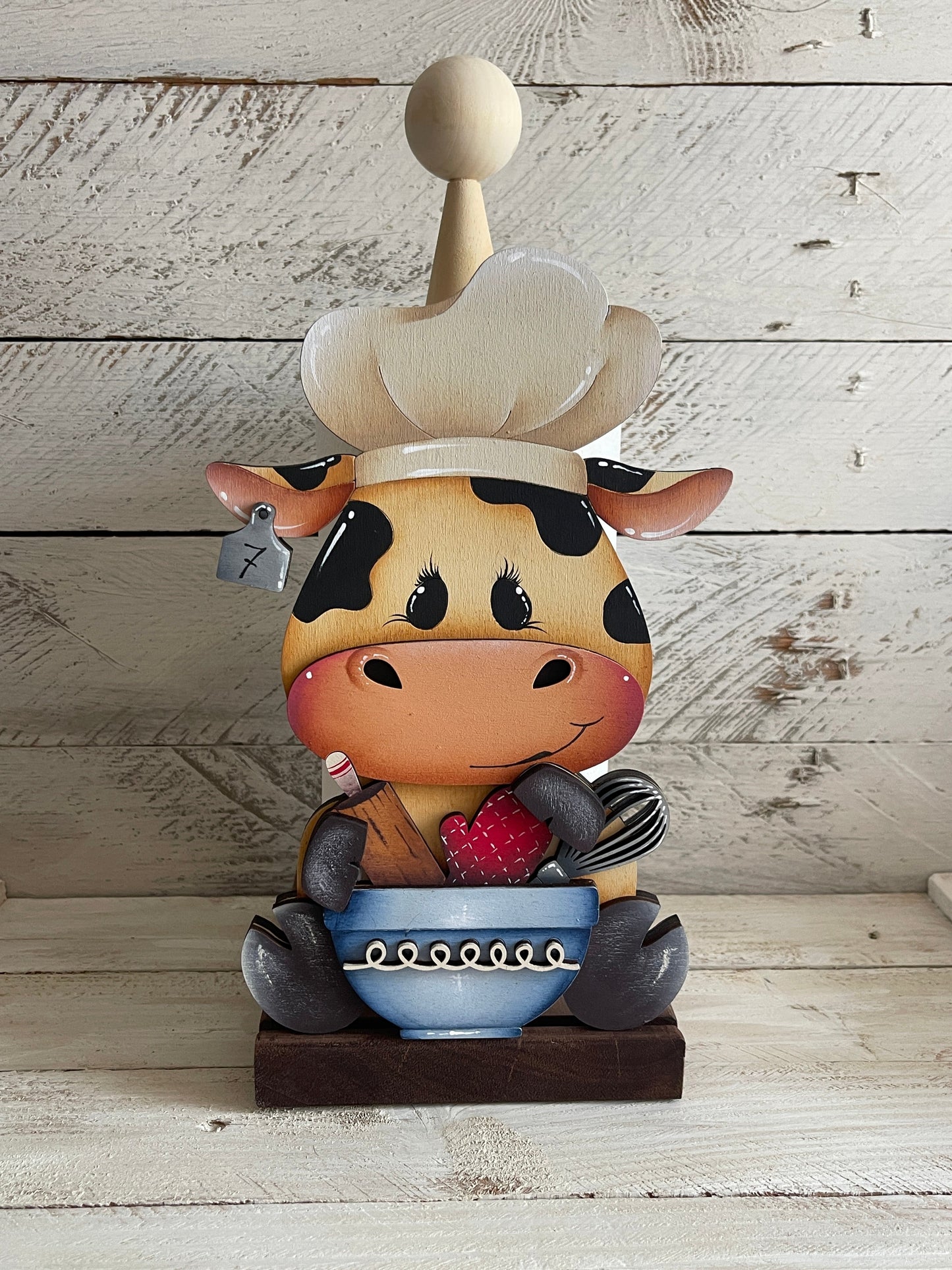 Mucca seduta con utensili da cucina Out of the Wood