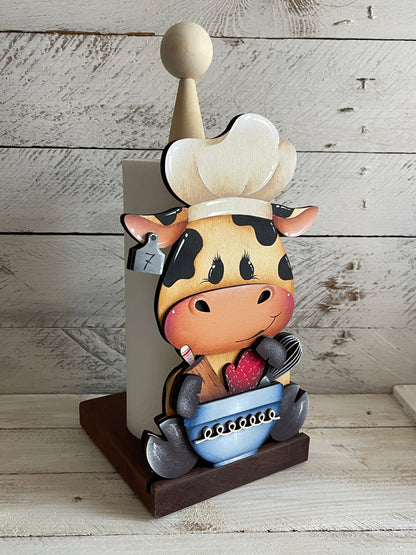 Mucca seduta con utensili da cucina Out of the Wood